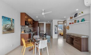 Uma cozinha moderna com armários de madeira, uma área de jantar com mesa e cadeiras redondas, e um ventilador de teto.