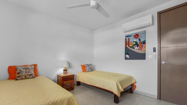 Ein Zimmer mit zwei Betten, einem Deckenventilator, einer Klimaanlage und einer Tür.