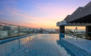 An infinity pool with a city view, a glass railing, and a modern architectural design. - Modern Apartment with a Pool (Puerto Vallarta)