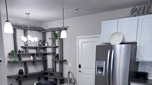 Een moderne keuken met granieten aanrechtbladen, roestvrijstalen apparatuur en witte kastjes.