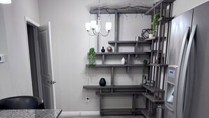 Een moderne keuken met een granieten aanrechtblad, roestvrijstalen apparatuur en een ingebouwde wandplank.