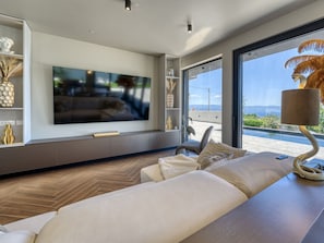 A modern living room with a large flat-screen TV, comfortable seating, and a view of the outdoors. - Black Imperium by Interhome (Mošćenička Draga/Sv. Jelena)