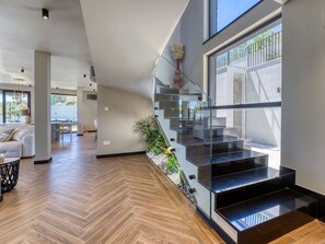 A modern interior with a herringbone wooden floor, a glass staircase, and a view of the outdoors. - Black Imperium by Interhome (Mošćenička Draga/Sv. Jelena)