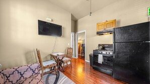 A compact kitchen with a black refrigerator, wooden cabinets, a stove, and a flat-screen TV mounted on the wall. - Lovely 1-bedroom apartment with AC in vibrant Sacramento (Sacramento)