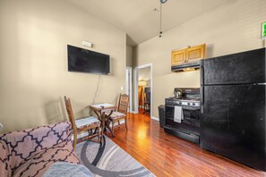 A compact kitchen with a black refrigerator, wooden cabinets, a stove, and a flat-screen TV mounted on the wall. - Lovely 1-bedroom apartment with AC in vibrant Sacramento (Sacramento)