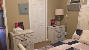 A bedroom with a bed, a nightstand, a dresser, a closet, and a wall-mounted air conditioner. - Lovely 1-bedroom apartment with AC in vibrant Sacramento (Sacramento)