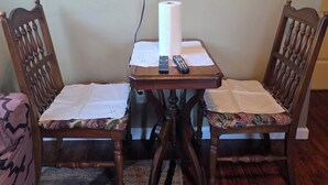 A small dining area with two wooden chairs, a table, a remote control, and a rolled-up paper towel. - Lovely 1-bedroom apartment with AC in vibrant Sacramento (Sacramento)