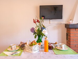 A breakfast setup with a vase of flowers, a bottle of orange juice, and a flat-screen TV mounted on the wall. - Apartment Niki by Interhome (Domaso)