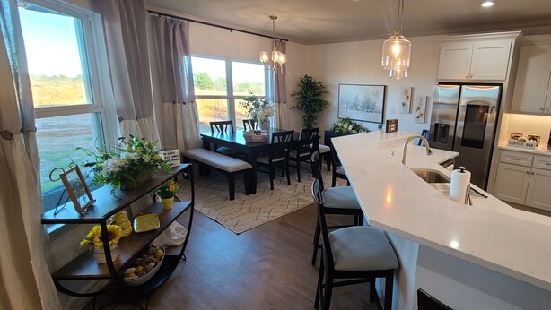 Een moderne keuken met een groot kookeiland, roestvrijstalen apparatuur en een eethoek met een bank.