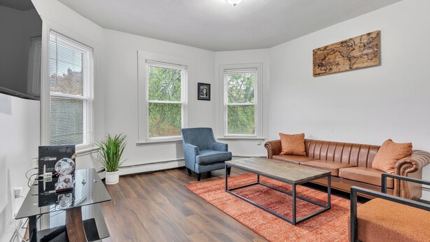 Ein modernes Wohnzimmer mit Sofa, Sessel, Couchtisch und einer Weltkarte als Wandkunst.
