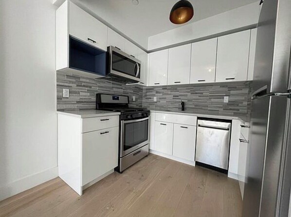A modern kitchen with white cabinets, a microwave, an oven, and a dishwasher. - Enjoyable 1-bedroom apartment with AC 
WiFi in charming Corona. (Corona)