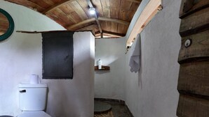 A compact bathroom with a white toilet, a small sink, and a shower area. - Finca Secreto Sur, A Hidden Paradise in the Jungle (Carara)