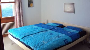 Une chambre à coucher avec un lit, une fenêtre avec des rideaux et un radiateur.