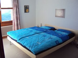 A bedroom with a bed, a window with curtains, and a radiator. - Plattas, (Flims Fidaz), 1045 by Interhome (Flims)