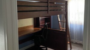 Una habitación con literas, un escritorio y una silla.