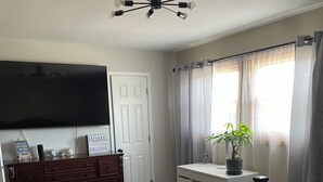 Un dormitorio con cama, cómoda, escritorio, televisor y ventilador de techo.