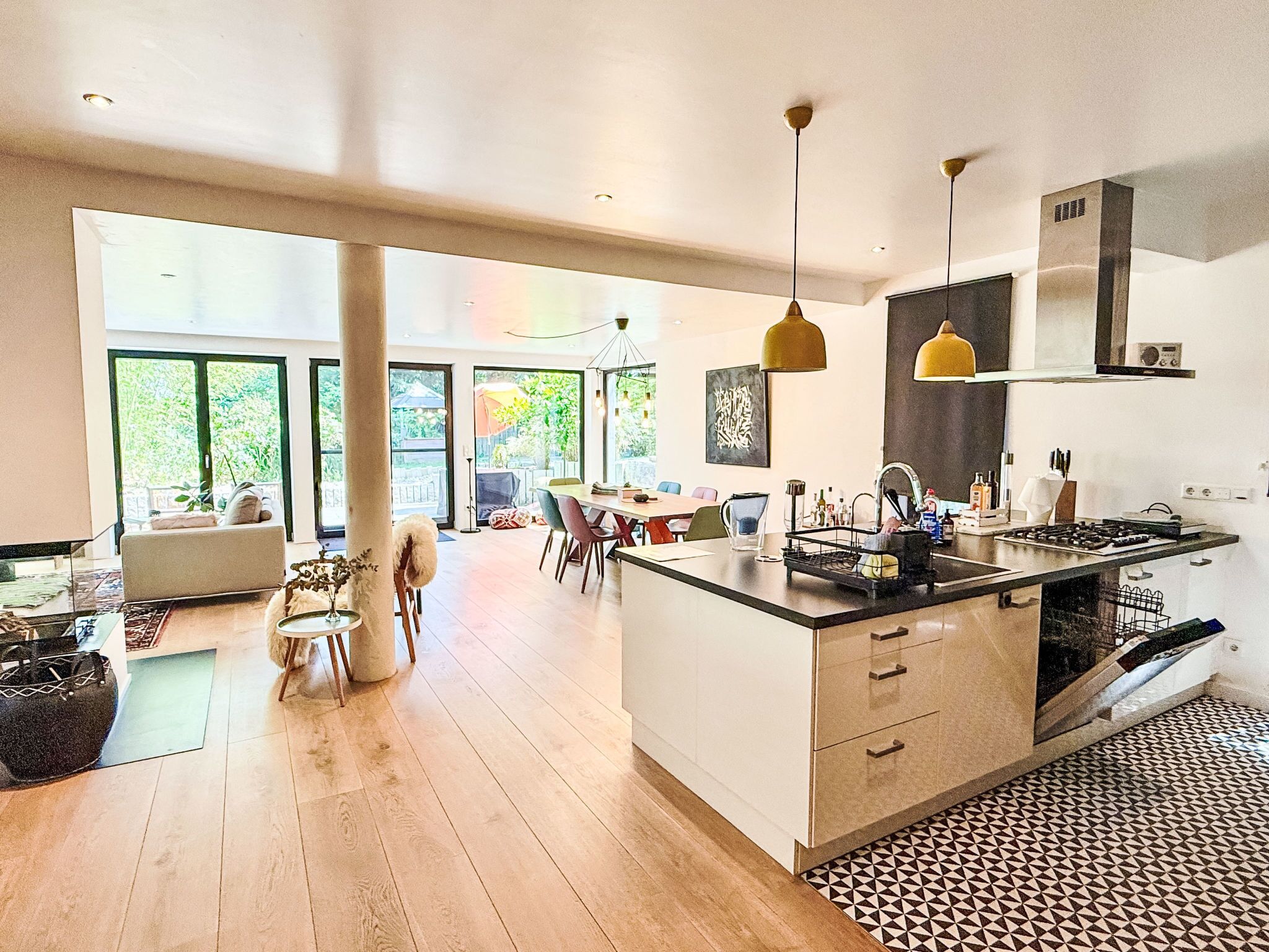 Una cocina moderna con una isla central, iluminación colgante y vistas al exterior.