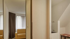 A hotel room with a bed, a small table, a sofa, and a window with curtains. - 2 Person Holiday Park Home in Nuernberg (Nuremberg)