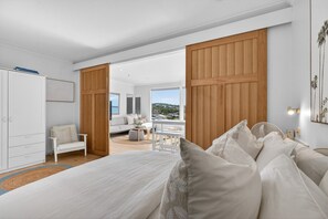 Ein modernes Schlafzimmer mit einem großen Bett, einem Schreibtisch und Blick ins Freie.