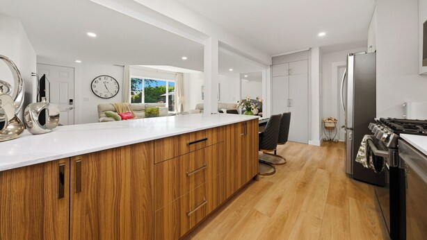 Una cocina moderna con armarios de madera, una isla grande, electrodomésticos de acero inoxidable y vistas al exterior.