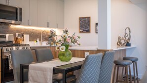 Una cocina moderna con zona de comedor, que incluye un jarrón verde con flores, un microondas y una estufa.