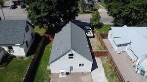 A residential area with a house featuring a sloped roof, a fenced yard, and a driveway.