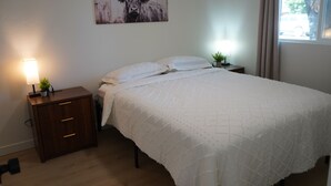 A bedroom with a bed, nightstands, a lamp, and a painting on the wall.
