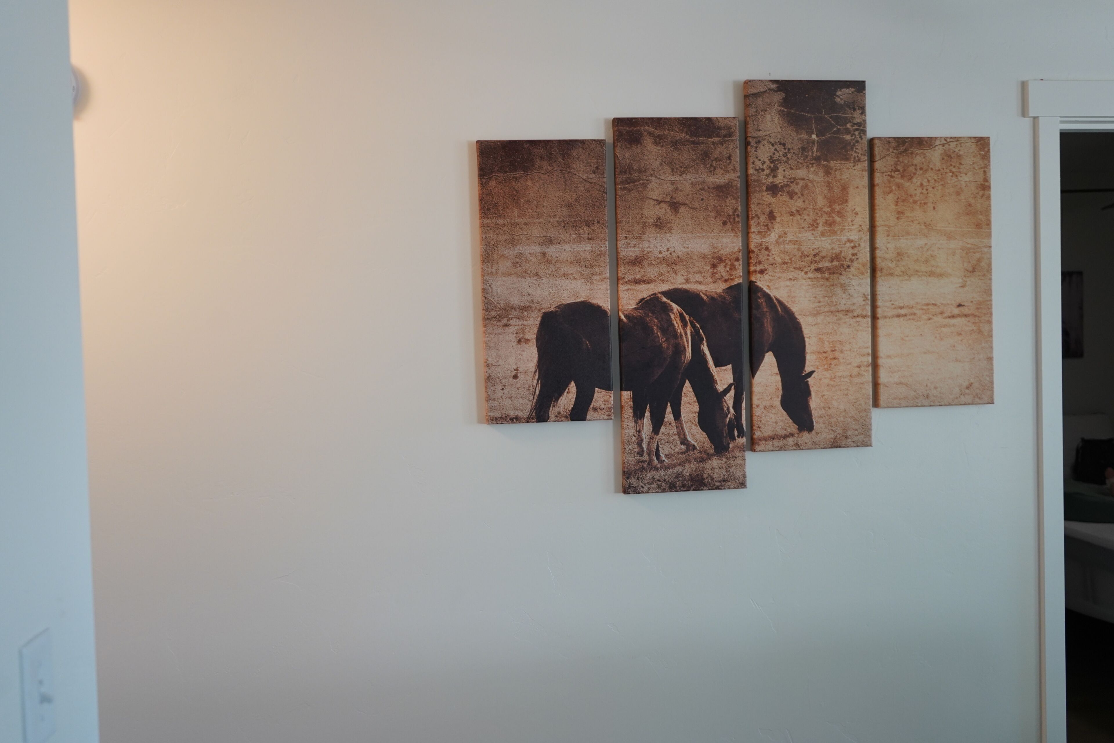 A wall with a three-panel artwork of horses.