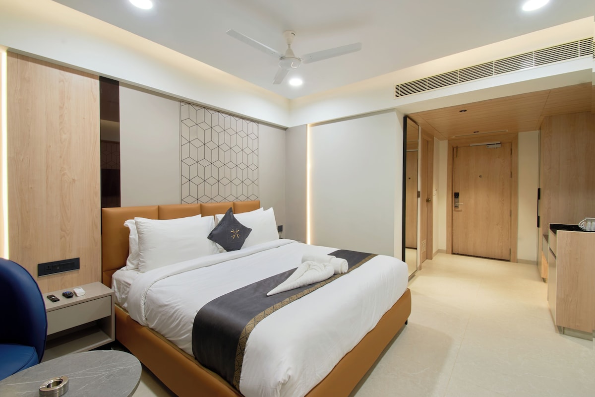 Quarto de hotel moderno com cama, mesa de cabeceira e escrivaninha com cadeira.