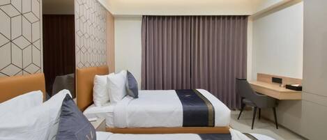A hotel room with two beds, a desk, and a chair.
