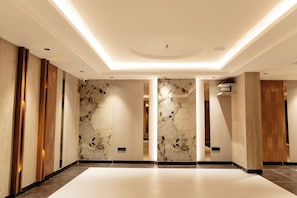 A spacious lobby with a marble wall, wooden panels, and a modern ceiling design. - ECKO Premier V Kondapur (Hyderabad)
