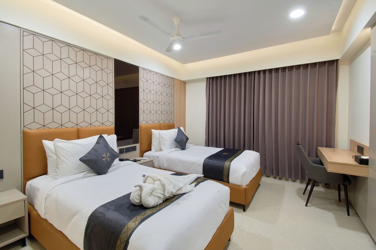 Quarto de hotel com duas camas, uma escrivaninha e uma cadeira.