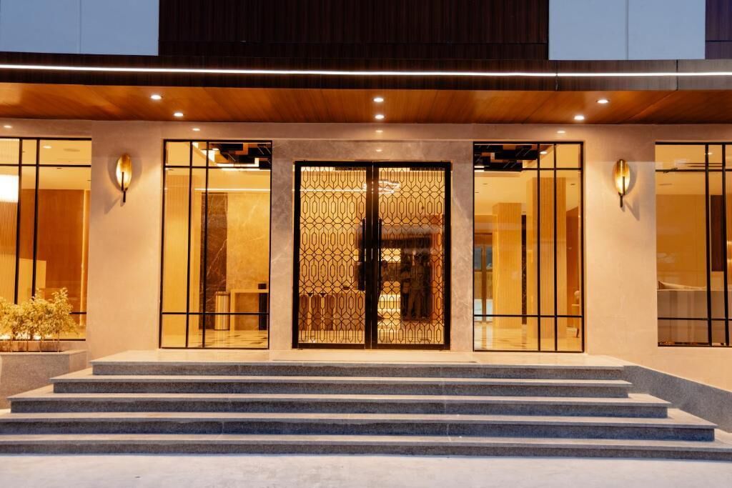 Entrada de hotel con un conjunto de escalones que conducen a un acceso doble decorado con un diseño geométrico.