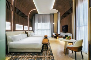 A modern hotel room with a large bed, a desk, a chair, and a dining table.