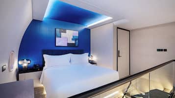 A modern bedroom with a bed, bedside tables, a nightstand, a wall-mounted artwork, and a door.