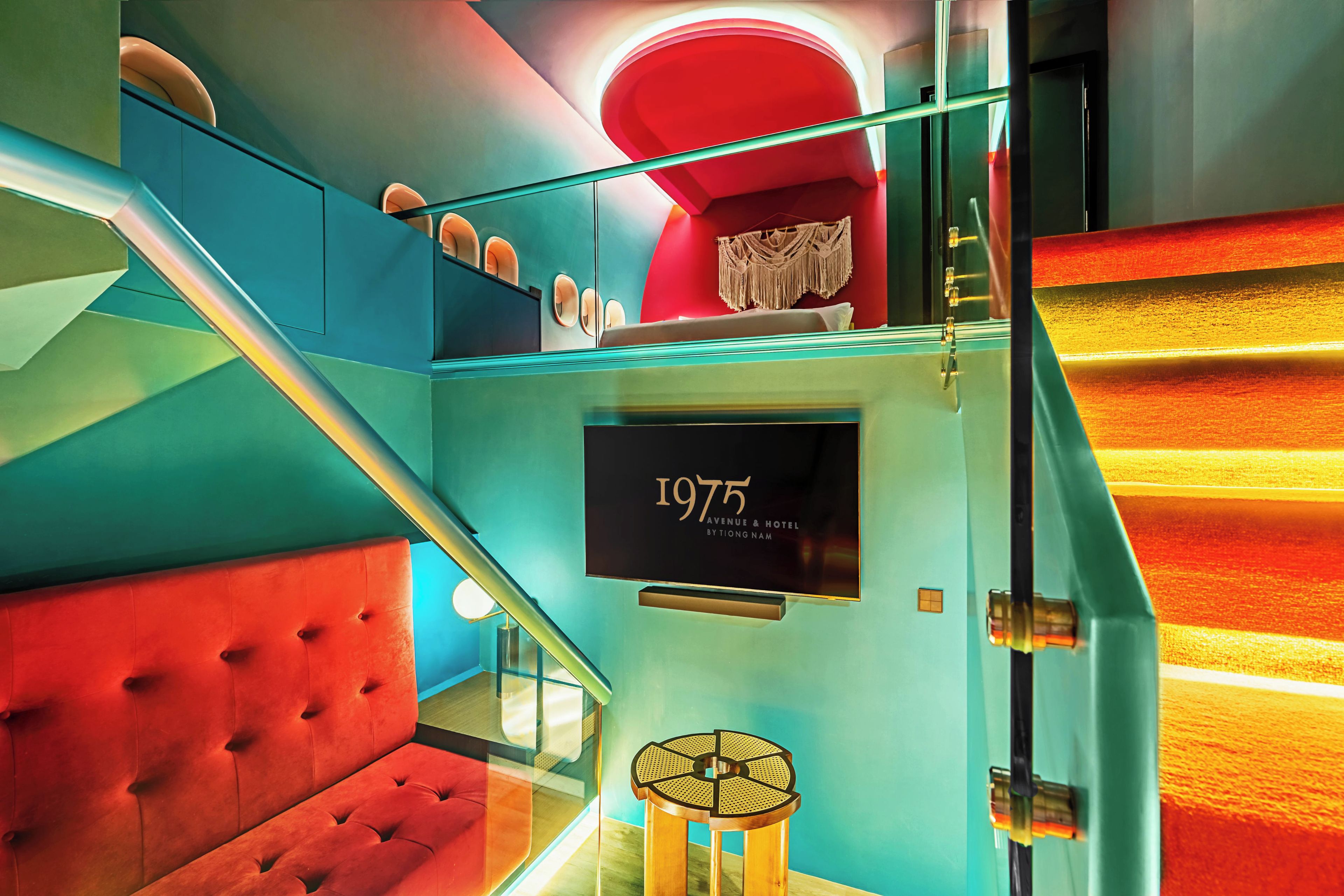 A staircase with a red cushioned seating area, a wall-mounted sign reading '1975 Avenue & Hotel by Tiong Nam,' and a decorative macramé piece.