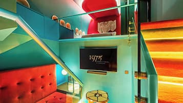A staircase with a red cushioned seating area, a wall-mounted sign reading '1975 Avenue & Hotel by Tiong Nam,' and a decorative macramé piece.