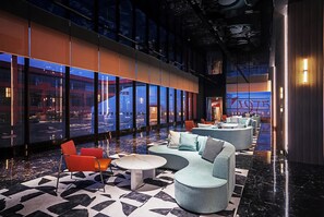 Eine moderne Lobby mit einer Sitzecke, einer Wasserspaltung und großen Fenstern mit Blick auf die Stadtlandschaft.