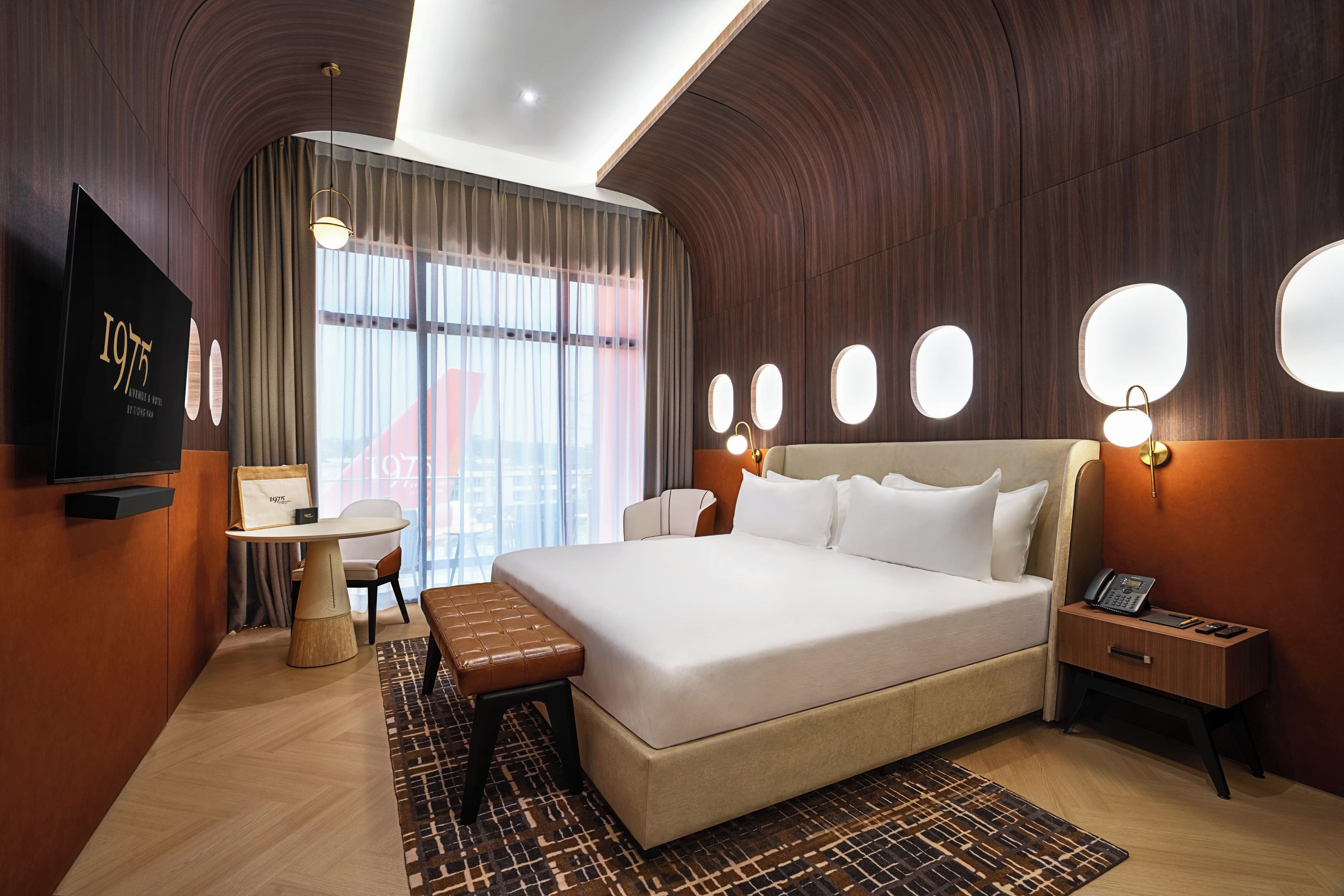 A hotel room with a large bed, a desk, a chair, a TV, and a window with curtains.