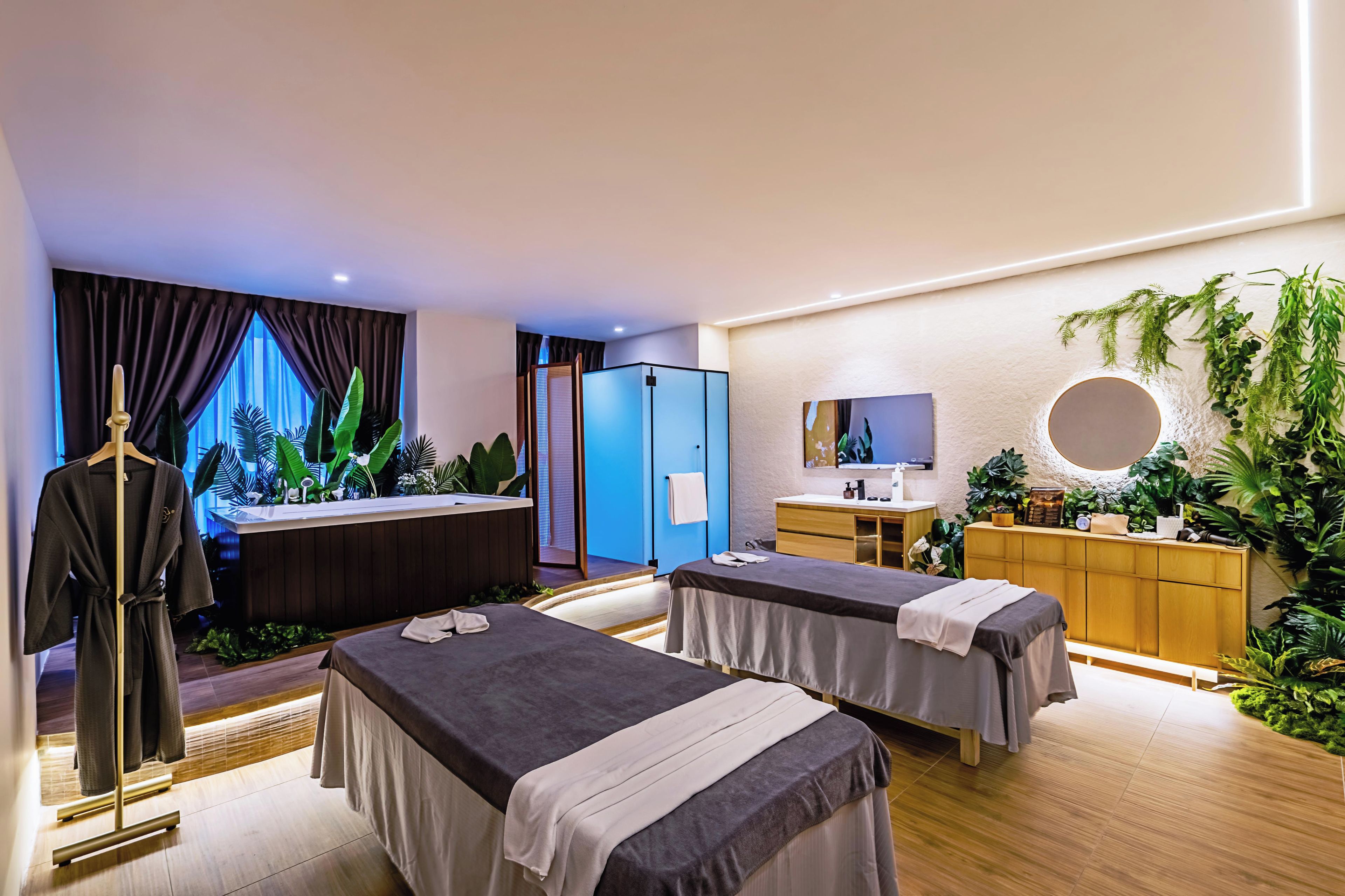 Ein Spa-Raum mit zwei Betten, einem Empfangstresen, einem Spiegel und einer großen Pflanze.