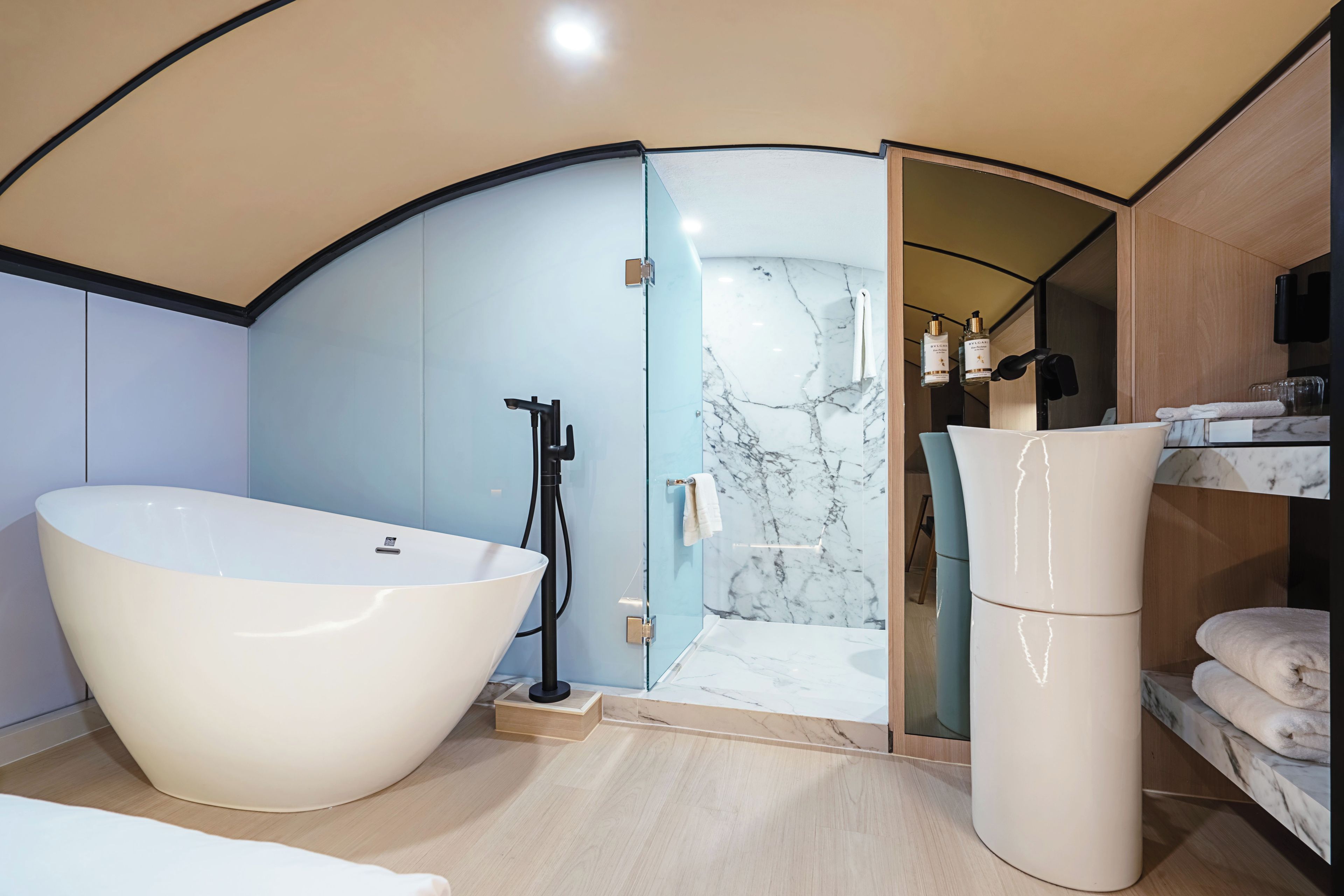 A modern bathroom with a large bathtub, a shower area, and a vanity with toiletries.