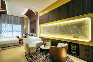 A modern hotel room with a large bed, a curved sofa, a small round table, and a unique wall-mounted light fixture. - 1975 Avenue & Hotel (Johor Bahru)