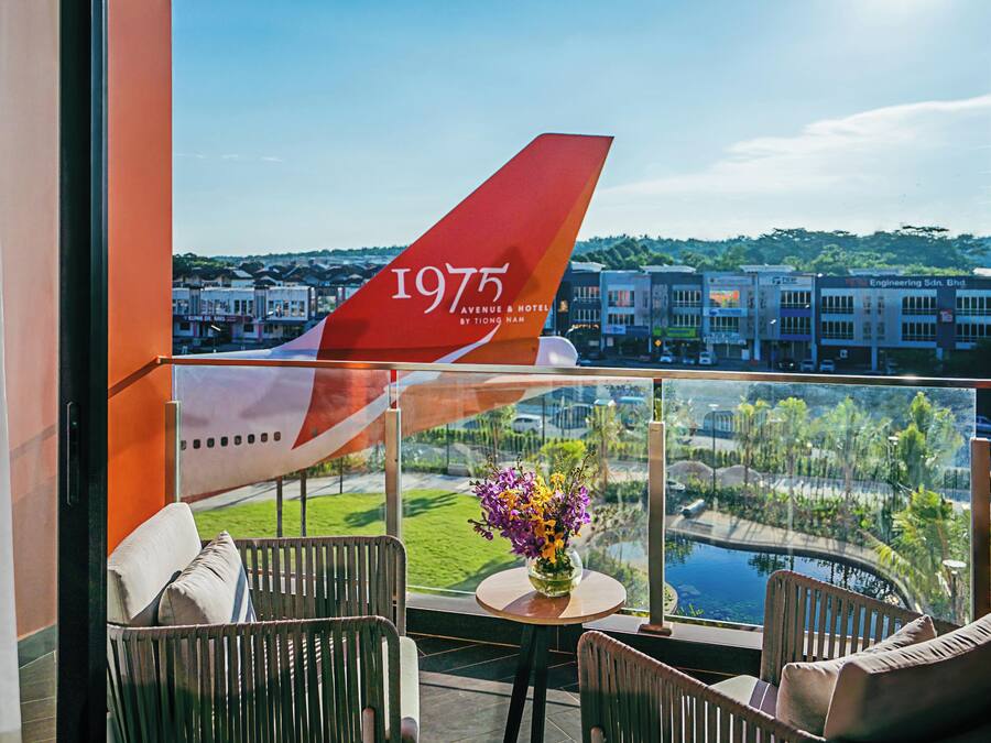 Un balcón con vista a un paisaje urbano y la cola de un avión grande.