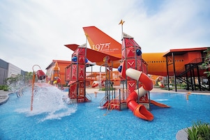 Parque acuático con toboganes y piscina, rodeado de edificios.