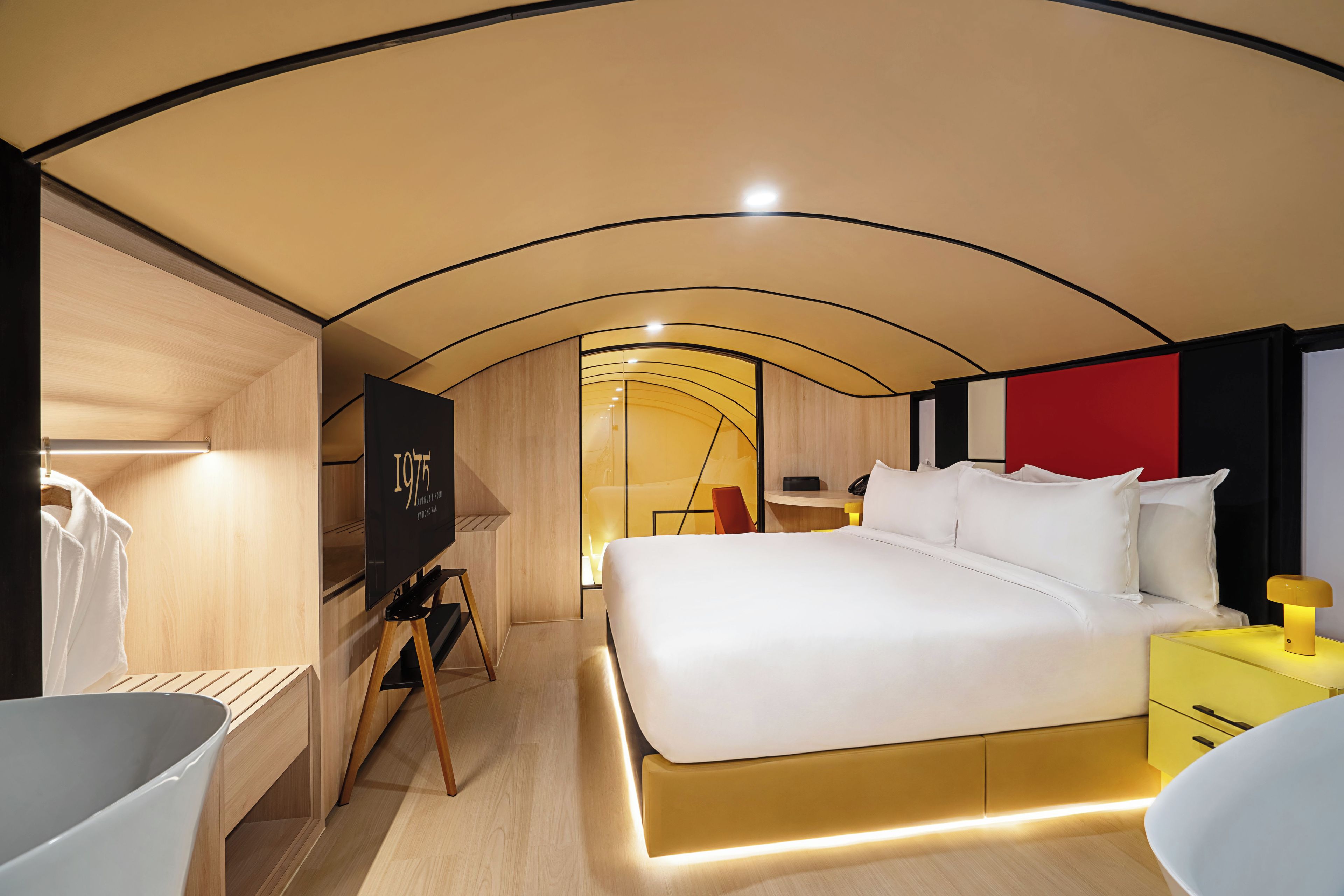 A modern hotel room with a bed, bedside table, and a television.