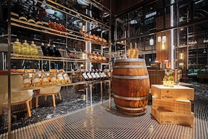 Un bar moderne avec des étagères remplies de bouteilles de différentes liqueurs, un grand tonneau en bois et un plancher ciré.