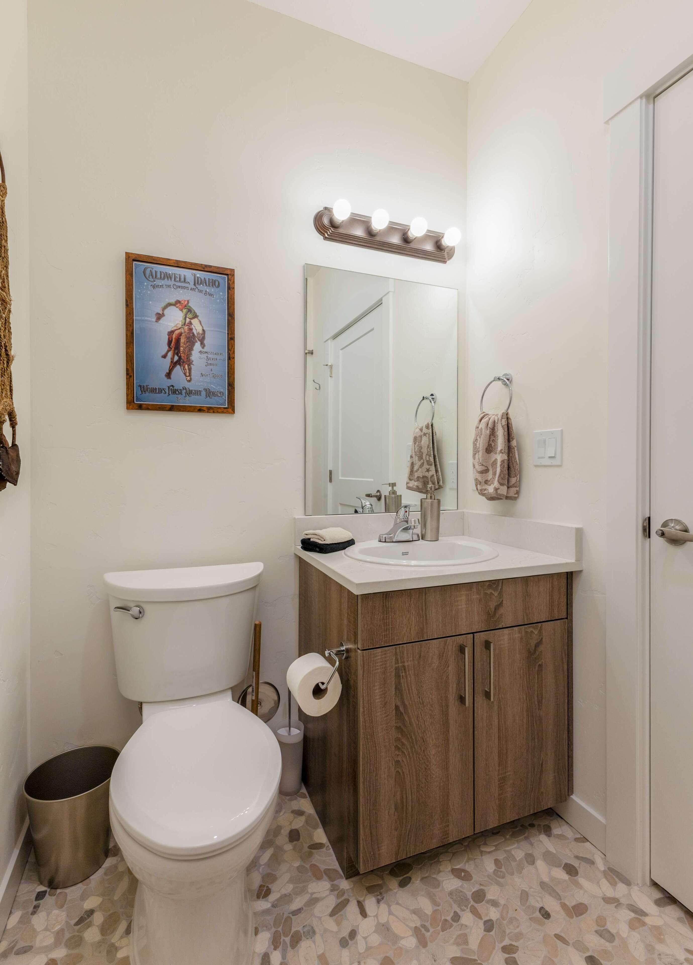 Ein Badezimmer mit Toilette, Waschbecken, Waschtisch, Spiegel und einem Bild an der Wand.