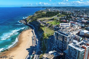 An aerial view of Beach Petite with a beach, buildings, and a road. - Beach Petite - Across from Beach - Walk to City (Newcastle)