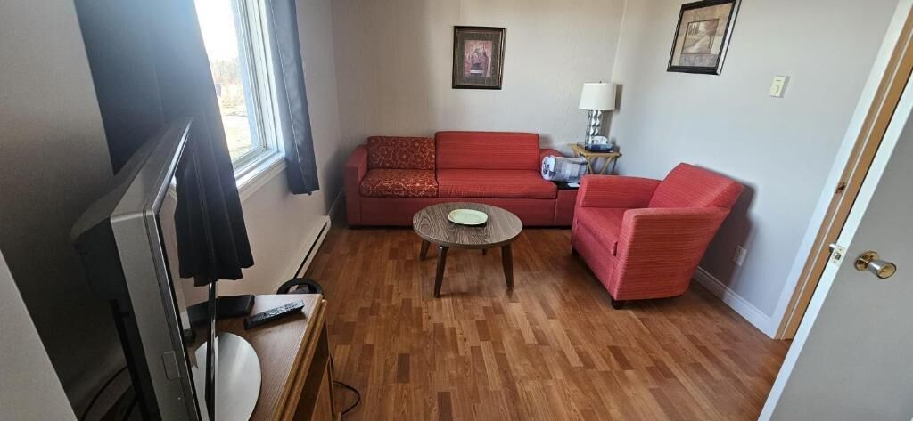 A living room with a red sofa set, a small round table, and a television.
