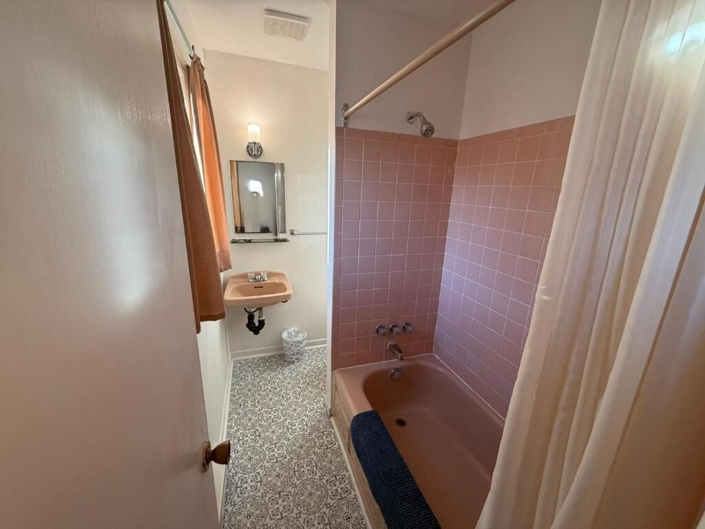A bathroom with a bathtub, a shower, a sink, and a mirror.